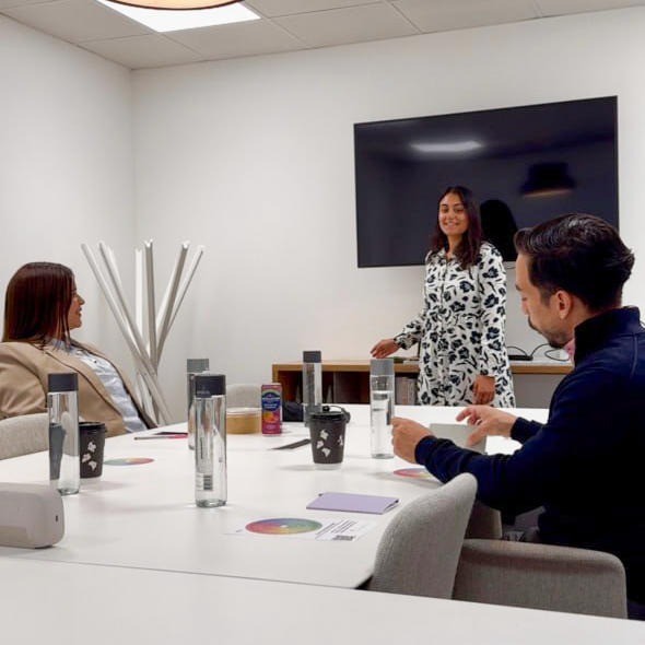 Team wellbeing session in a meeting room with a facilitator and colleagues around a table