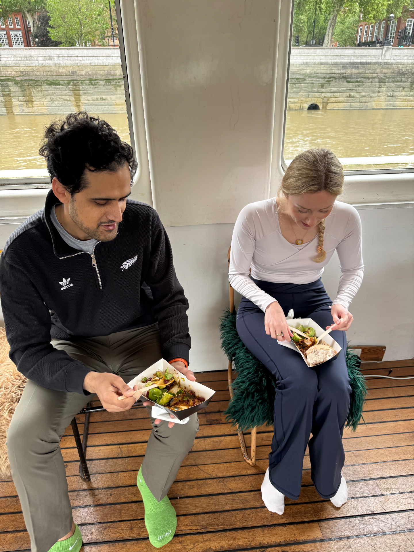 Two guests seated on the waterside boat venue at a Mindful Brunch Club retreat, sharing brunch trays